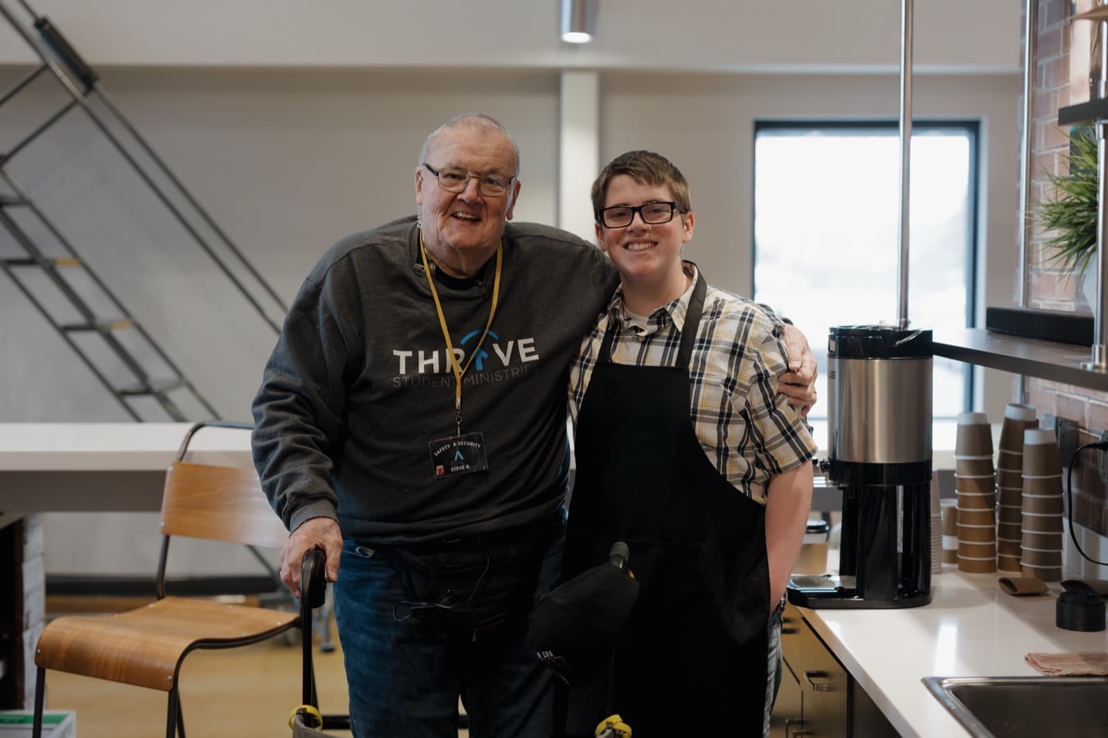 Two volunteers smiling behind the coffee bar.