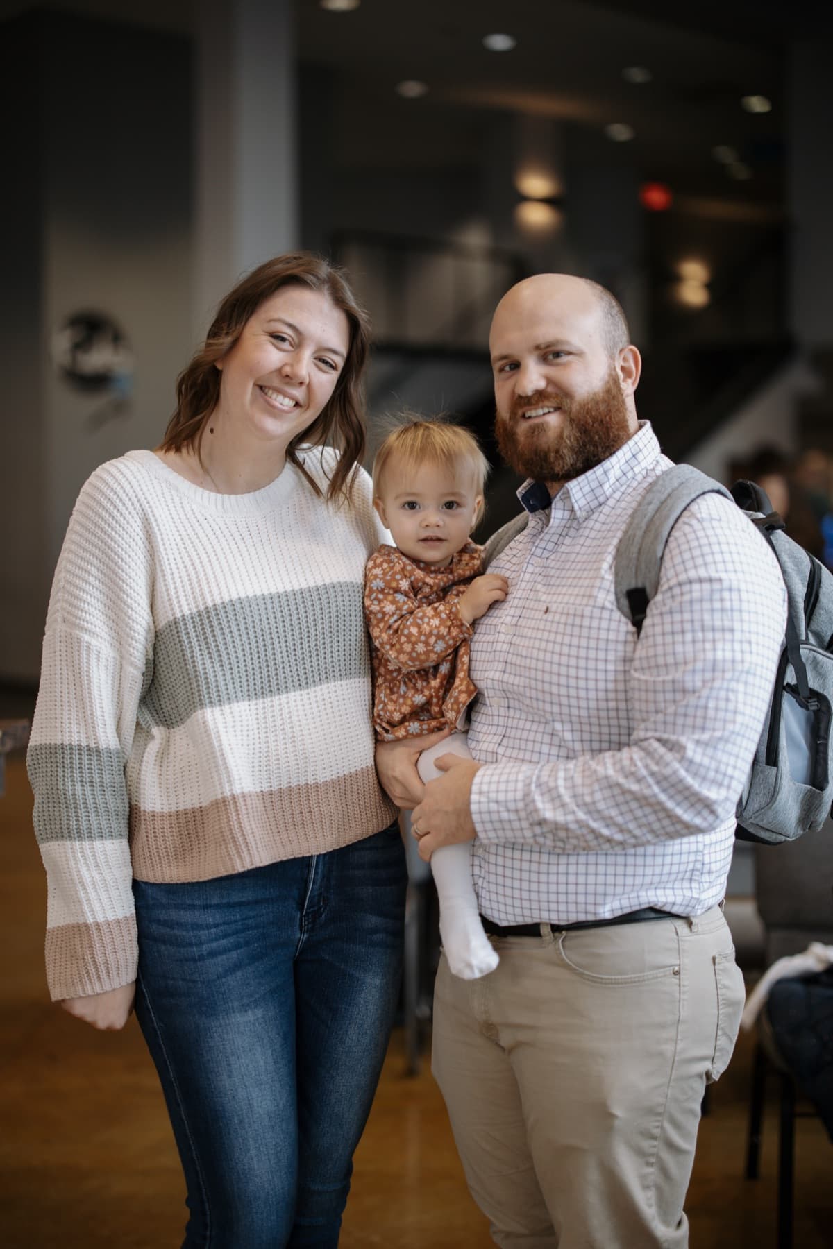 A young couple holding their baby in the church lobby.